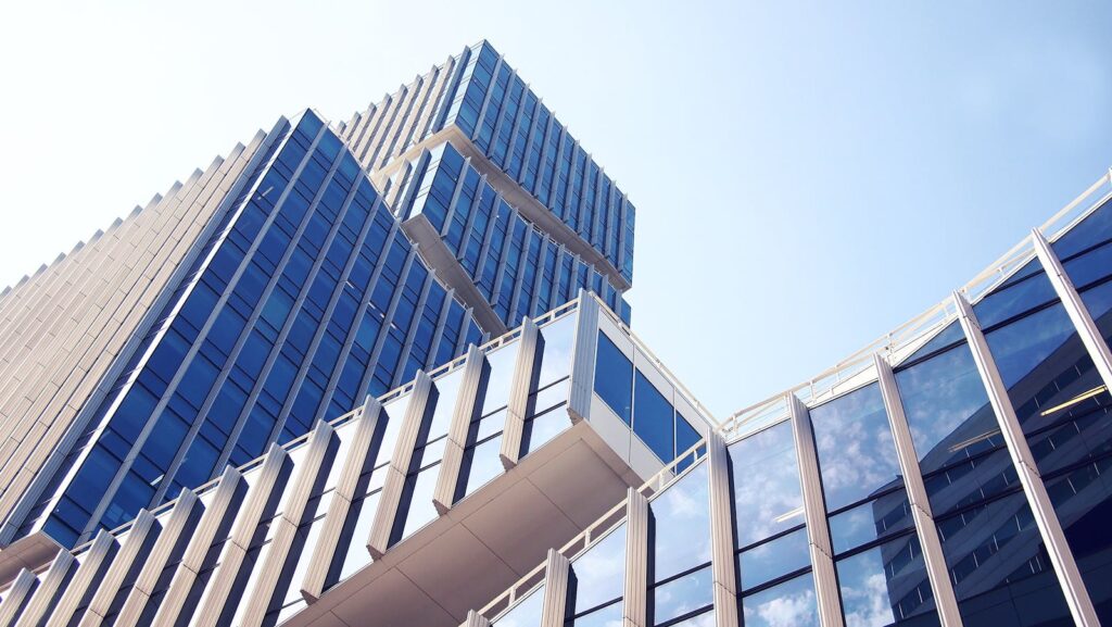 Low-angle shot of a modern skyscraper with reflective glass design under a clear blue sky.