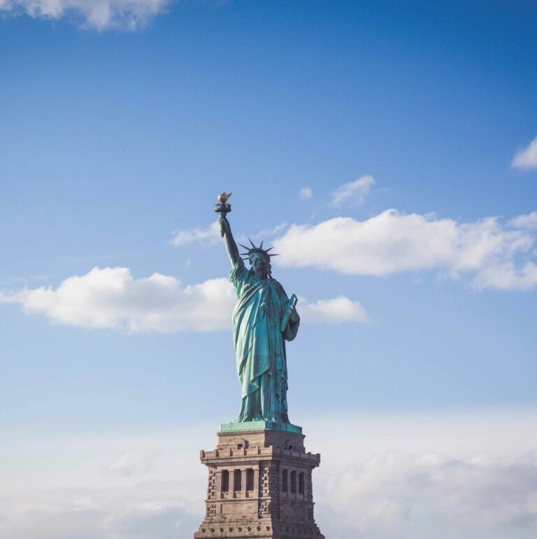 Statue of Liberty, New York under white and blue cloudy skies